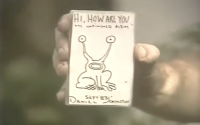 Daniel Johnston holds up the cover of Hi, How Are You